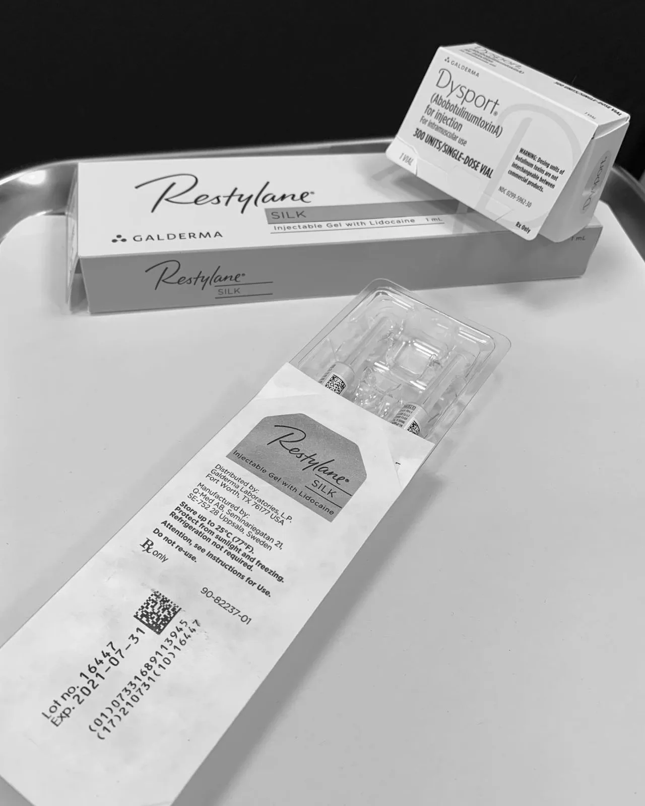 Restylane Silk and Dysport injectable filler products displayed with packaging and syringes